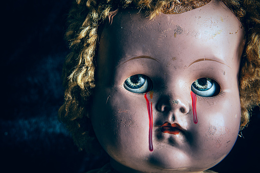 A creepy old doll with blood dripping from her eyes.