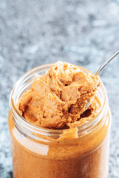 istock Spoon dipping into a glass jar with crunchy peanut butter. 1336486885
