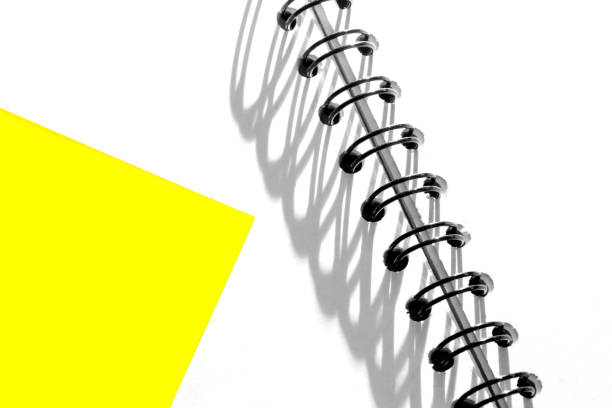 Creative closeup abstract image of a yellow gelatin printing filter isolated on plain white spiral bound diary pages with beautiful shadow patterns. Copy space.