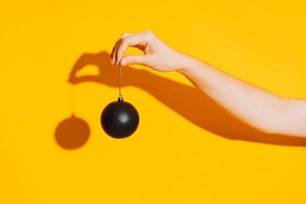 istock Hand holding black matte bauble on yellow background 1336488581