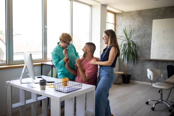 istock Two women teasing their colleague while he works in office 1336489375