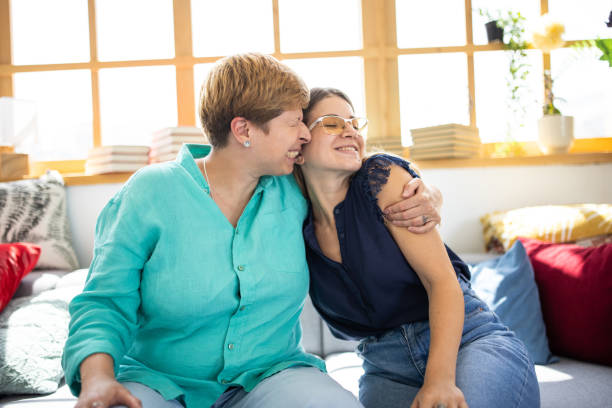 istock Two sisters embracing each other while relaxing on sofa at home 1336490816