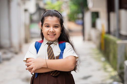 Outdoor Portrait image of young Asian/ Indian female student wearing school uniform and going to school.