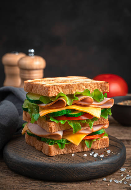istock Sandwich with ham, cheese, tomatoes and cucumbers on a brown background 1336490940