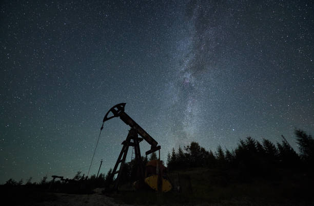 istock Oil pump jack at night time under starry sky. 1336491088