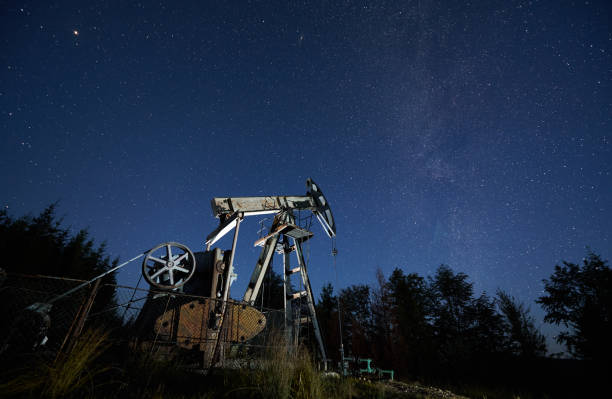 istock Oil field with petroleum pump jack under night starry sky. 1336491103