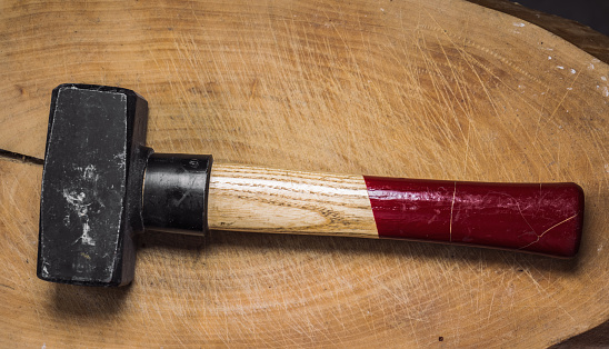 a hammer with a red handle lay on a wooden board