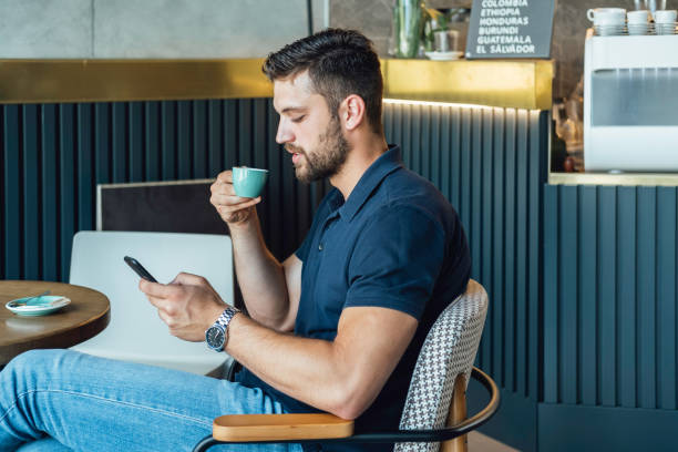 istock Handsome Businessman Using Mobile Phone while Drinking Coffee in a Cafe 1336492734