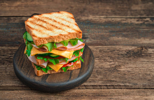 sanduíche de clube com presunto, queijo, legumes e torrada grelhada em um fundo marrom de madeira - sandwich club sandwich ham turkey - fotografias e filmes do acervo