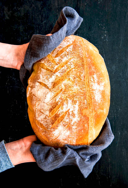 istock Female hands hold freshly baked bread on a black background. top view 1336495125