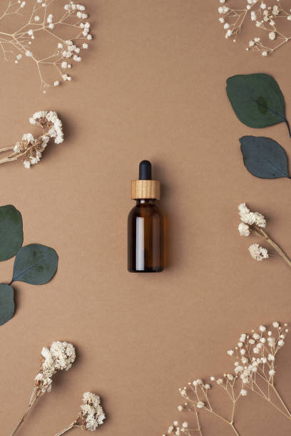 istock Cosmetic bottle with flowers and eucalyptus on brown background. Flat lay 1336495576