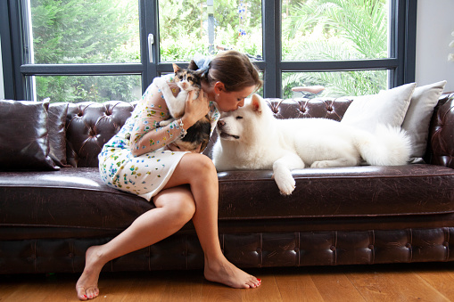young woman petting her cat and dog at home