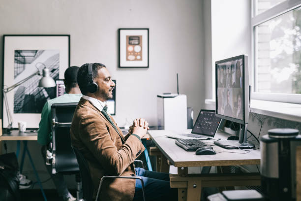 Programmer having a team meeting online Indian programmer having a video call with teammates at work. voip stock pictures, royalty-free photos & images