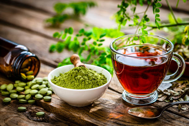 tè matcha, moringa in polvere e pillole sul tavolo di legno - chinese medicine herb pill nutritional supplement foto e immagini stock