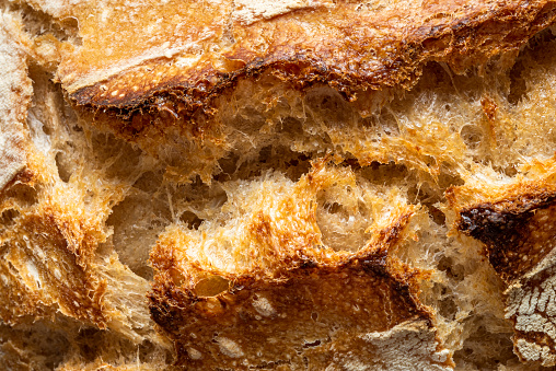 Close-up with the crust of homemade sourdough bread. Delicious loaf of bread, macro details, top view