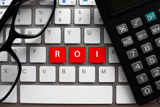 istock Top view of calculator, glasses and computer keyboard with a red button written with ROI or Return On Investment. 1336505146