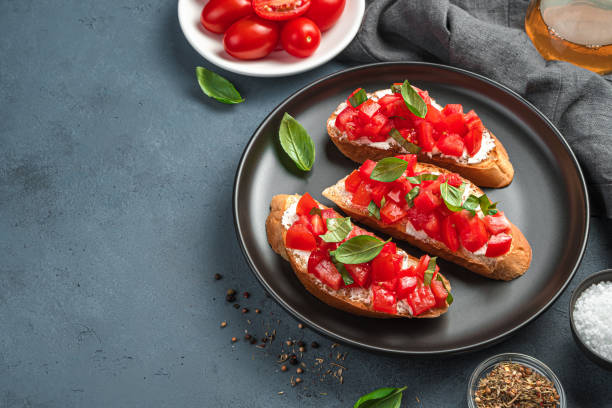 istock Traditional bruschetta with tomatoes, basil and cream cheese on a dark background 1336506369