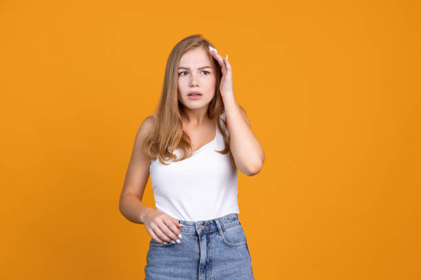 istock Emotional expression. Thoughtfull young woman portrait showing emotions on orange studio background 1336507363