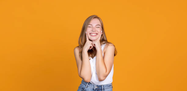 istock Keep smiling. Cheerful young girl smiling on orange bakground 1336507376