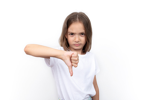 Unhappy little girl showing thumb down gesture.