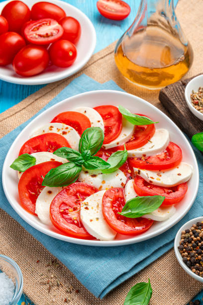 istock Caprese salad with tomatoes, mozzarella and basil on a blue background 1336510201