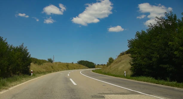 istock Asphalt road on a sunny summer day in green fields on blue cloudy sky background. 1336510881