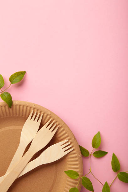 istock Eco friendly disposable dishes with green leaves on pink background. Zero waste, eco friendly, plastic free background. Vertical photo 1336513709