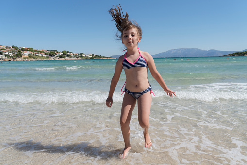 Happy little girl jumping in the sea