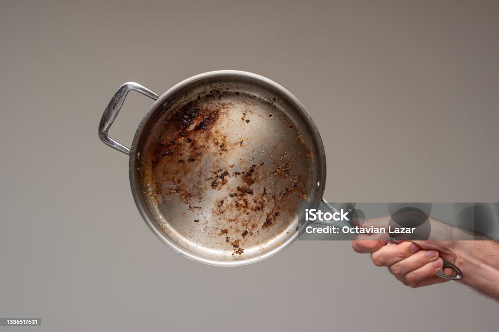Dirty oily burnt metal frying pan held in hand by male hand. Dirty oily burnt metal frying pan held in hand by male hand. . Cooking Pan Stock Photo