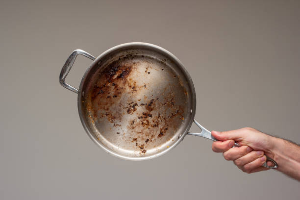 Dirty oily burnt metal frying pan held in hand by male hand. stock photo