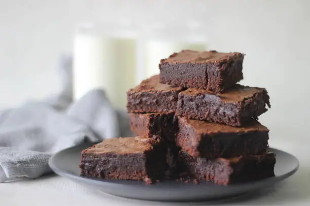 Home baked fudgy chocolate brownie sliced in square blocks and stacked one over the other. Shot on white background