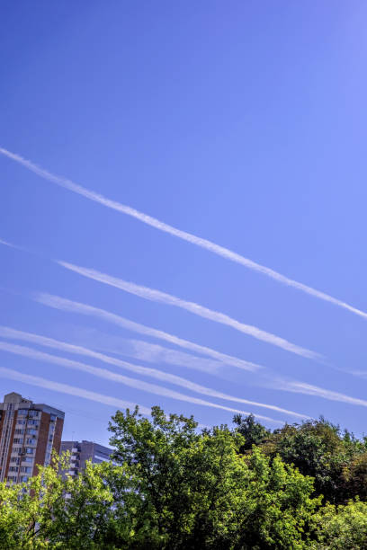 istock White airplane chemtrails in the blue sky. Geo engineering. 1336518412