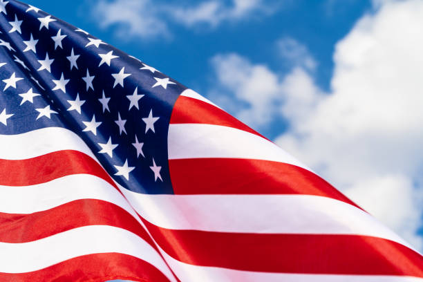 istock American flag on flagpole waving in the wind against white clouds 1336519673