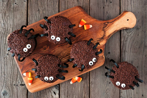 Halloween spider cupcakes on a wooden serving platter over wood Halloween spider cupcakes, above view on a wooden serving platter over a dark wood background halloween cupcake stock pictures, royalty-free photos & images