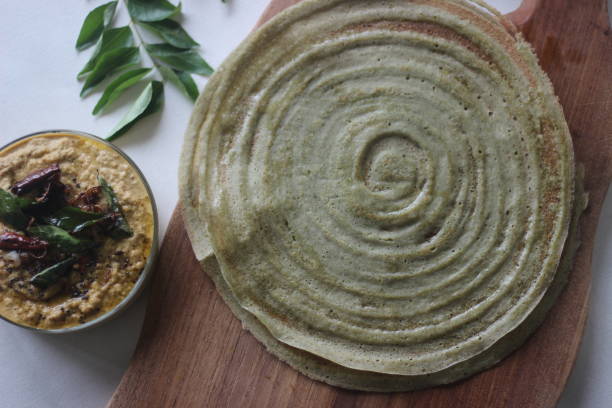 タンパク質豊富なムーン豆クレープ、地元ではペサラッタとして知られています。それはドーサのように見えますが、発酵衣で作られたものではありません。円形のテクスチャを示す展開さ� - moong dal ストックフォトと画像