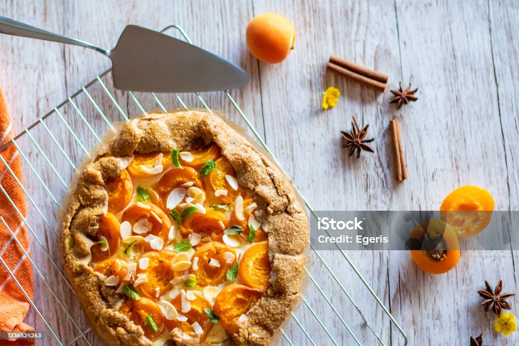 Apricot galette pie cake placed on wooden background with cooking tools on the side Crostata Stock Photo