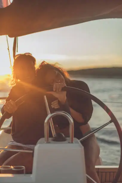 Photo of Mother and daughter steer a sailboat at dusk