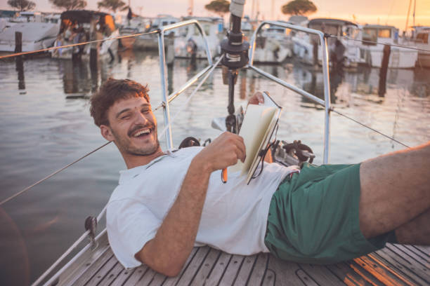 joven con libro de dibujo se relaja en proa de velero, anochece - 3504 fotografías e imágenes de stock