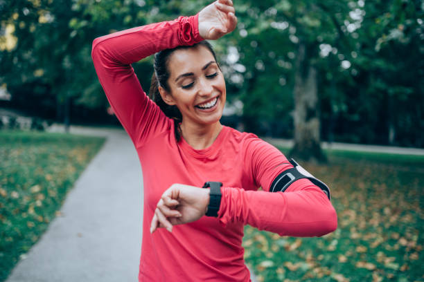 sportliche junge frau, die die zeit nach dem joggen überprüft. - fitness tracker stock-fotos und bilder