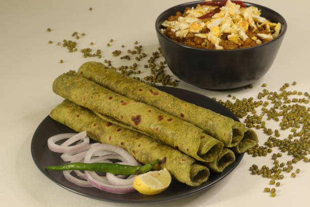 全粒粉で作られたインドのフラットブレッドは、純粋なほうれん草とスパイスで混練しました。上にスクランブルエッグと緑の月豆の肉汁と一緒に提供されます。 - moong dal ストックフォトと画像