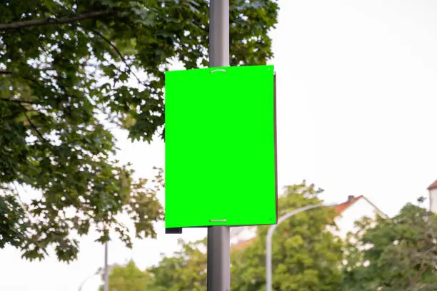 Mockup of a poster on a street lamp. Template for an election campaign poster outdoor. Blank advertisement board with no people in the city. Place for a commercial ad.