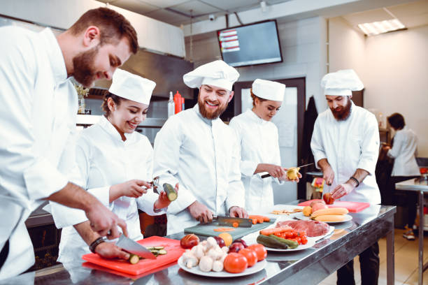 istock Smiling Colleagues In Restaurant Kitchen Preparing Single Dish With Vegetables Together 1336532912