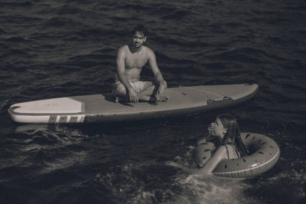 istock Young couple floating on a SUP and inflated ring 1336540304