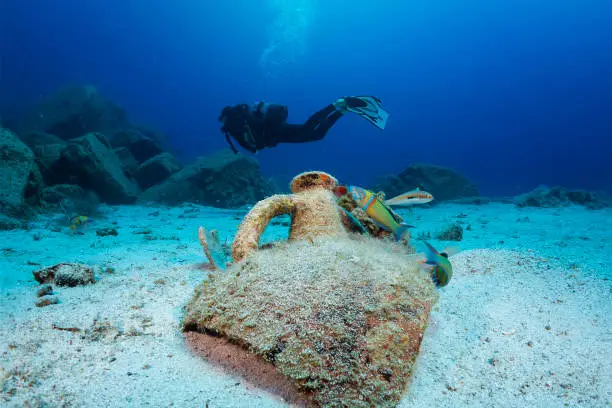 Scuba diving in Greece: an ancient, Greek Amphora with a scuba diver silhouette behind