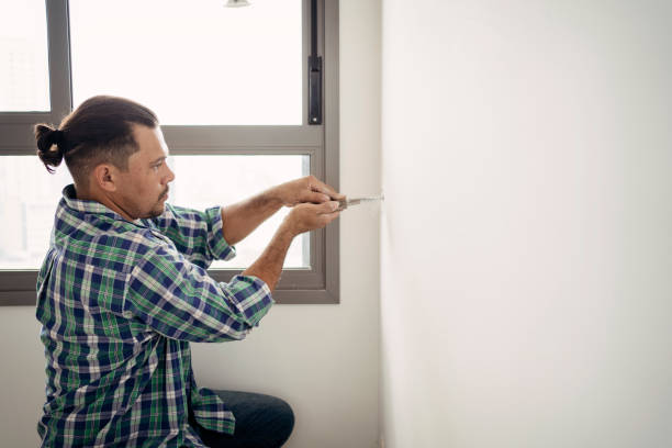 istock Electrician cutting drywall for electrical installation 1336542813