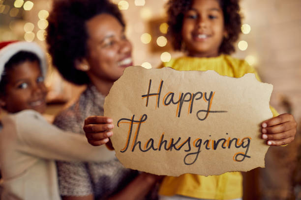 primer plano de una familia negra sosteniendo el letrero de feliz día de acción de gracias en casa. - family american culture black child fotografías e imágenes de stock