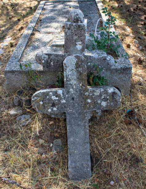 istock Two old stone crosses as tombstones in an graveyard, dry grass background; sunlight and shadow 1336547403