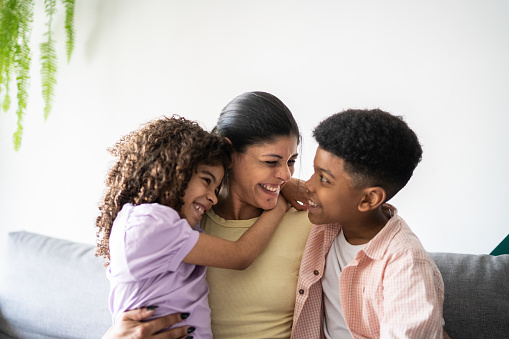 Woman and two kids smiling at home