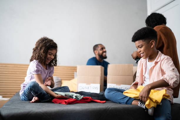 istock Parents with children sorting out clothes in boxes to donate at home 1336548492