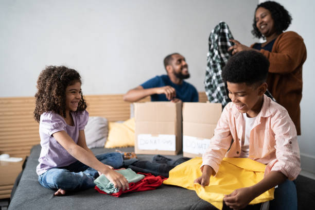 Parents with children sorting out clothes in boxes to donate at home